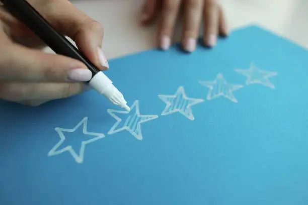 Photo of Person draws five stars in the recommendations with white felt-tip pen reviews