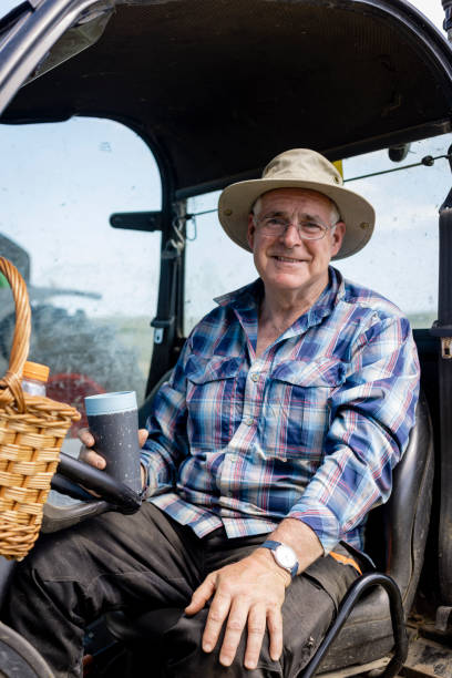 A Farmer Sitting in an Off Road Vehicle A male farmer wearing a checked shirt and hat sitting in an all terrain vehicle in a field in Embleton, Northumberland. He is looking at the camera and smiling while working on the farm and cultivating land. car portrait men expertise stock pictures, royalty-free photos & images