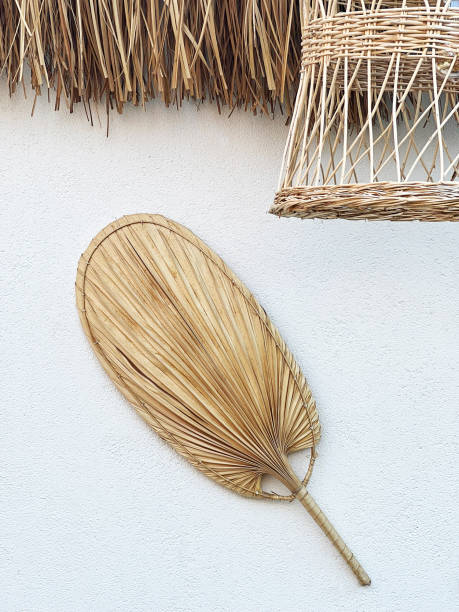 Macro of Boho Wall Decoration. Stylish boho garden wall decoration with elegant accessories like straw hand fan, rattan pendant light. Minimalistic concept of home decor.