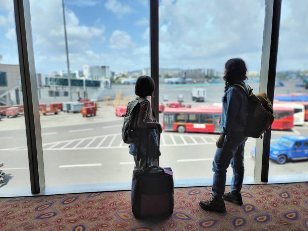 MOther and daughter waiting at the airport terminal Mother and daughter looking outside through the transparent glass while waiting at the airport terminal india airport stock pictures, royalty-free photos & images
