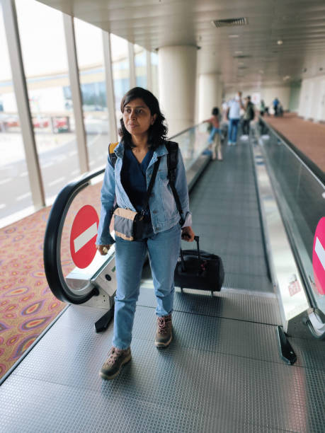Woman traveller carrying her luggage on the airport Woman traveller carrying her luggage on the airport on moving walkway india airport stock pictures, royalty-free photos & images
