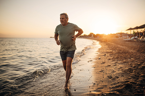 A man jogs alone on the sand by the seashore