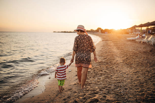 babcia i wnuk spacerują brzegiem morza - men footprint beach sunset zdjęcia i obrazy z banku zdjęć