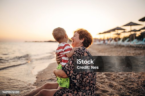 istock Grandmother and grandson on the sandy beach, summer vacation 1409876130