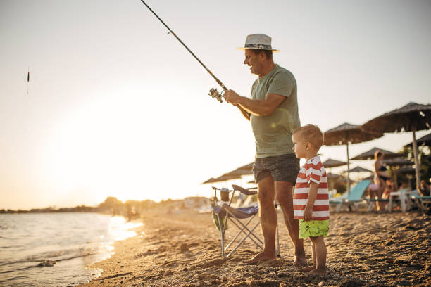 istock Fishing reel, grandfather teaching grandson to fish 1409876498