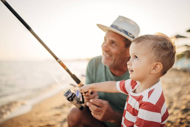 istock Fishing reel, grandfather teaching grandson to fish 1409876509