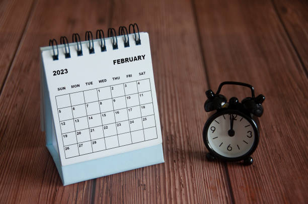 2023 년 2 월 12 시를 가리키는 알람 시계가있는 나무 테이블에 흰색 책상 달력. - 12 oclock 뉴스 사진 이미지