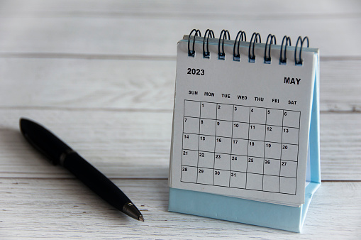 Calendario de escritorio blanco de mayo de 2023 con bolígrafo negro sobre mesa de madera. photo