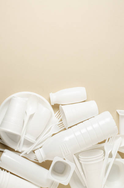 istock Disposable white plastic tableware on a beige background. The concept of nature pollution. Copy space. 1409877567