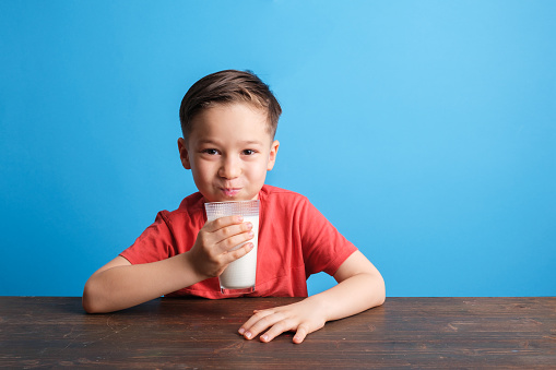 Child drinking milk on blue background