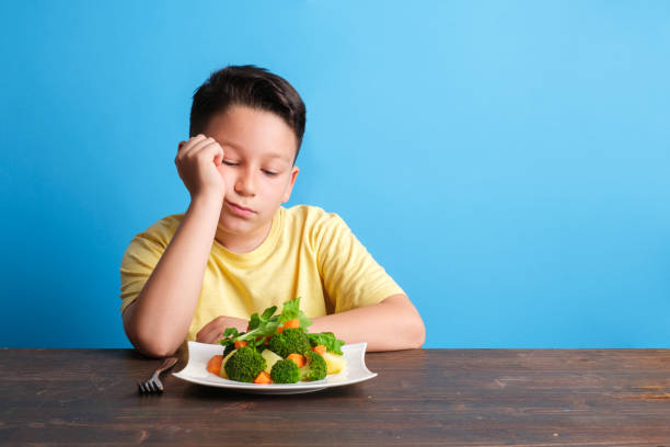 子供は野菜を食べなければならないことに非常に不満です - cute disgust carrot caucasian ストックフォトと画像