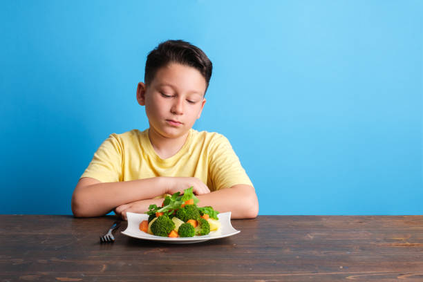 子供は野菜を食べなければならないことに非常に不満です - cute disgust carrot caucasian ストックフォトと画像