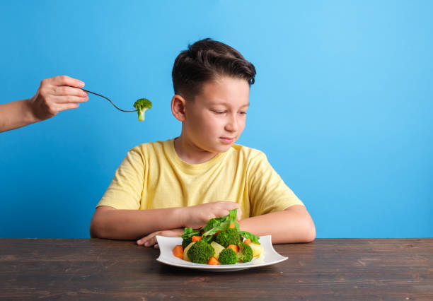 子供は野菜を食べなければならないことに非常に不満です - cute disgust carrot caucasian ストックフォトと画像
