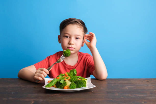 子供は野菜を食べなければならないことに非常に不満です - cute disgust carrot caucasian ストックフォトと画像