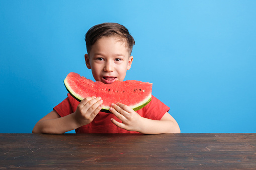 Child eating watermelon on blue background