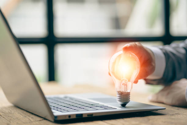 istock energy saving concept businessman holding a light bulb on a laptop with bright light 1409886254