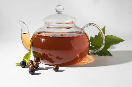 Blackcurrant tea in a transparent bowl on a light background