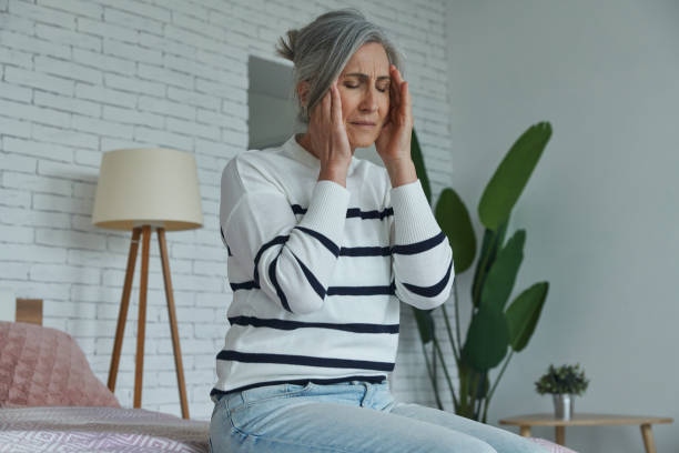 istock Senior woman suffering from headache while sitting on the bed at home 1409887600