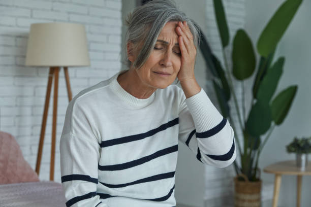 istock Depressed woman touching head while sitting on the bed at home 1409887618