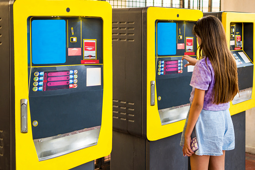Ticket machine in a metro station. Little girl loading the ticket to card.