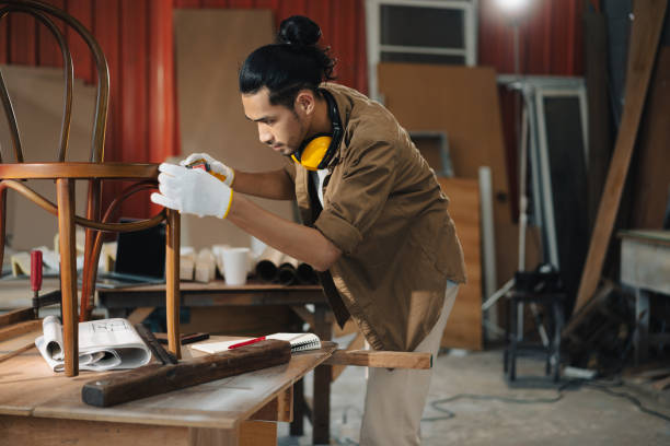 el joven asiático carpenter usa una cinta métrica para medir la silla en el banco de trabajo en el taller de carpintería de carpintería de artesanía. - the end wood timber construction fotografías e imágenes de stock