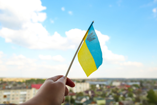 Defocus Ukraine flag. Large national symbol fluttering in blue sky. Support and help Ukraine, Independence Constitution Day, National holiday. Hand holding flag. Save Mariupol. Crisis. Out of focus.