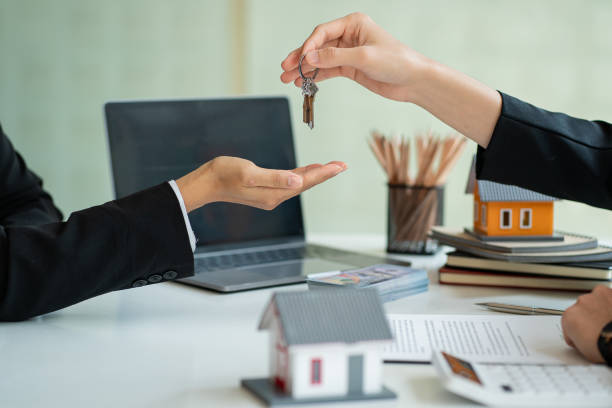 사업가가 열쇠를 쥐고있는 주택 판매 담당자 에이전트는 고객에게 열쇠를 제공합니다. 주택 구매 및 주택 보험 아이디어 - apartment manager key giving 뉴스 사진 이미지