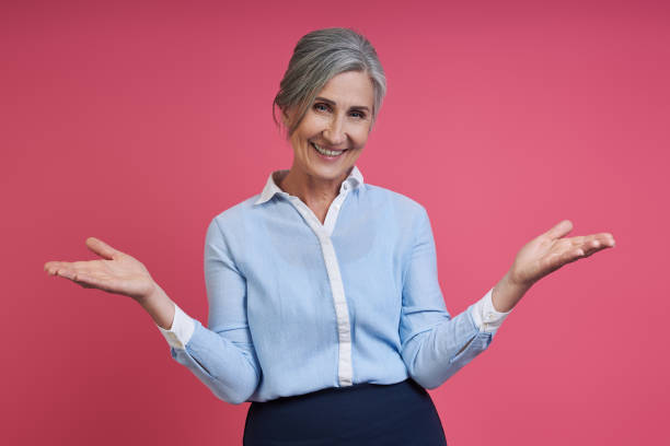istock Happy senior woman gesturing while standing against pink background 1409890248