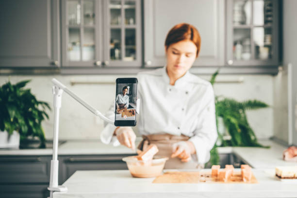 Food blogger showing process of making cakes online. stock photo