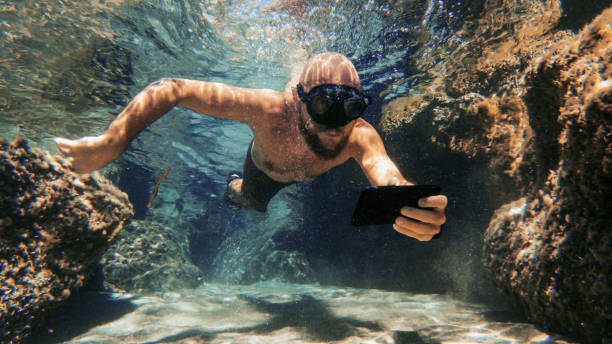selfie avec téléphone portable sous l’eau en mer: dépendance aux médias sociaux - men naked water male photos et images de collection