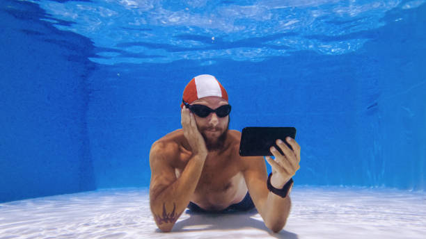 binge watching avec un téléphone portable sous l’eau: dépendance aux médias sociaux - men naked water male photos et images de collection