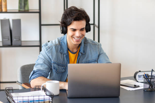 istock Young freelancer sitting sitting at the table at home. Studying, distance learning, online education concept. Happy male student or entrepreneur using laptop computer working in modern office 1409893192