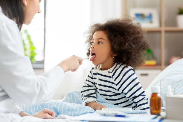 doctor checking sick girl's throat at home - boğaz ağrısı stok fotoğraflar ve resimler