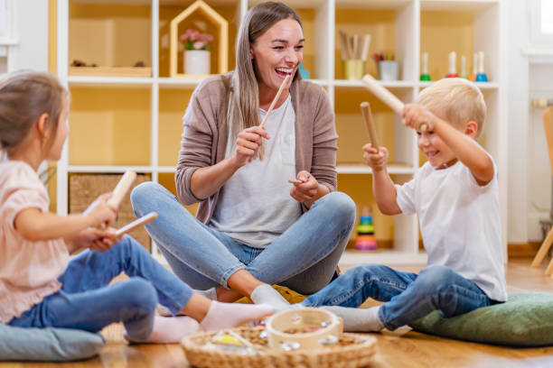 istock Kindergarten teacher with children sitting on the floor having music class, using various instruments and percussion 1409894594