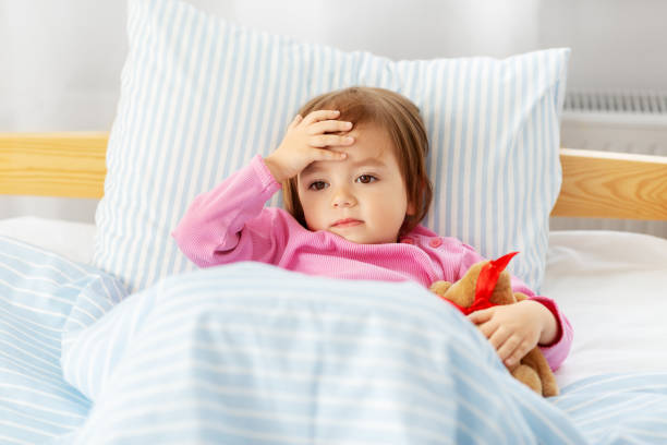 sick little girl lying in bed at home stock photo