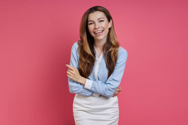 istock Happy young woman keeping arms crossed while standing against colored background 1409894883