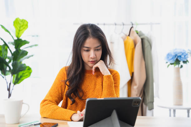 istock Asian woman sitting at home working at her desk with laptop computer. 1409896228