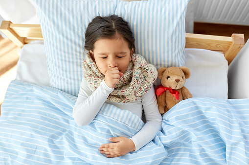 Sick girl child with teddy bear sleeping on bed at hospital - concept of medial treatment, illness and childcare