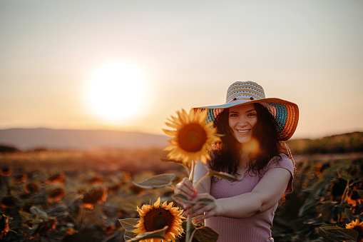 Woman enjoying beautiful sunset in sunflower field
