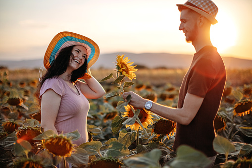 Two people enjoying sunset together in sunflower field