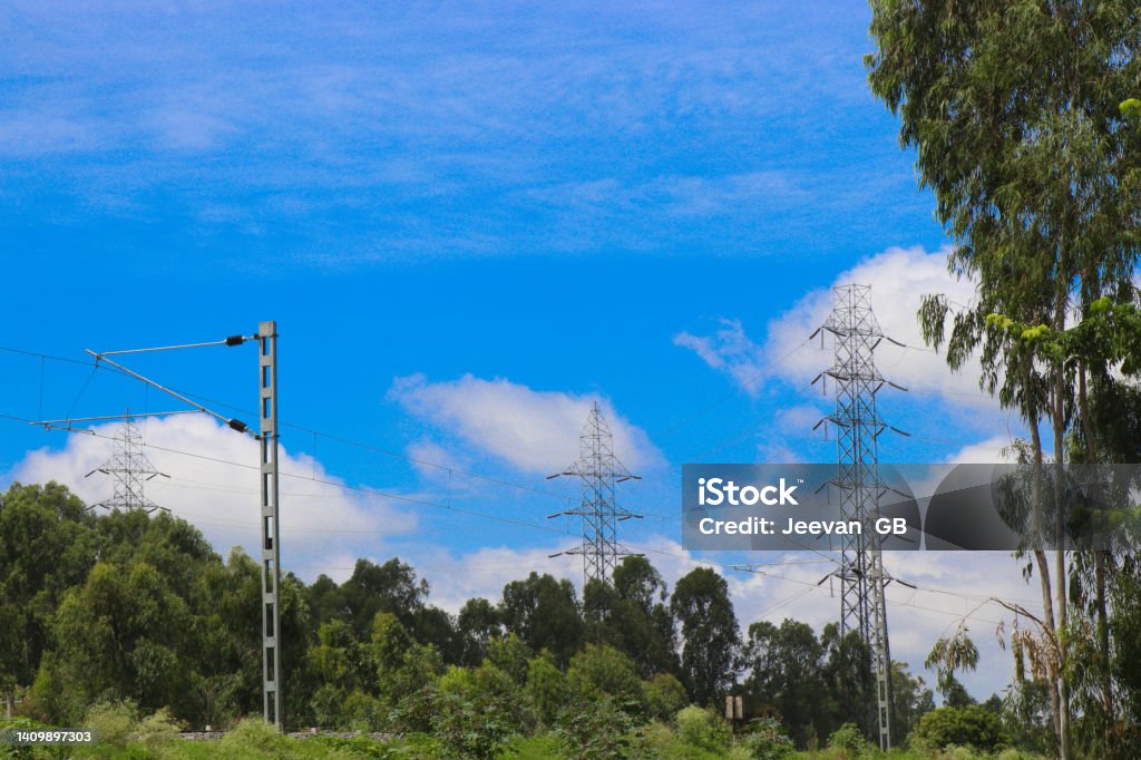 Electricity pole or electric post running through forests along with a view of electric train catenary against sky background Architectural Column Stock Photo
