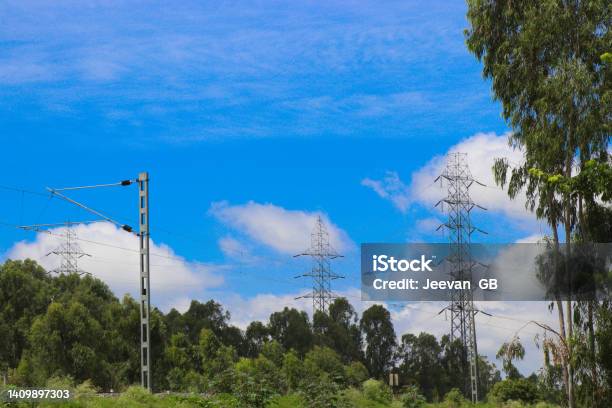 Electricity Pole Or Electric Post Running Through Forests Along With A View Of Electric Train Catenary Against Sky Background Stock Photo - Download Image Now