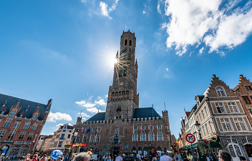 Bruges, Belgium. 16 July 2022. Central Bruges with belfry bell tower, many tourists walking on the street.