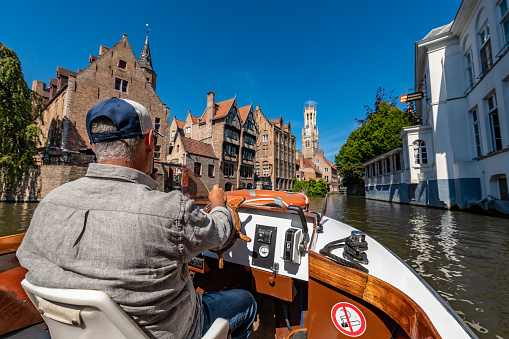 Bruges, Belgium - October 11 2019: Horse-drawn carriage with tourists and stone bridge on lake of love in background .