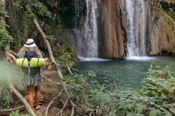 Beautiful view of the woman and the waterfall. A beautiful photo of a young woman standing next to a natural waterfall.