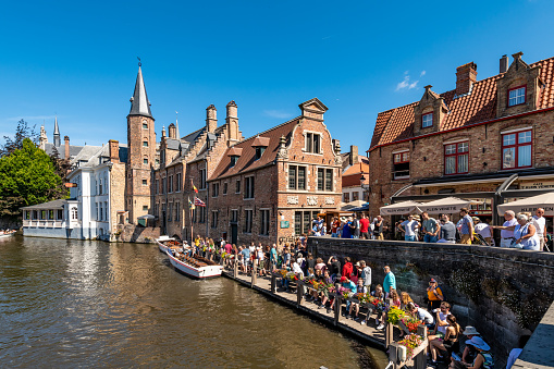 Bruges, Belgium. 16 July 2022. Tourists queue for a boat tour of Bruges on a sunny day.