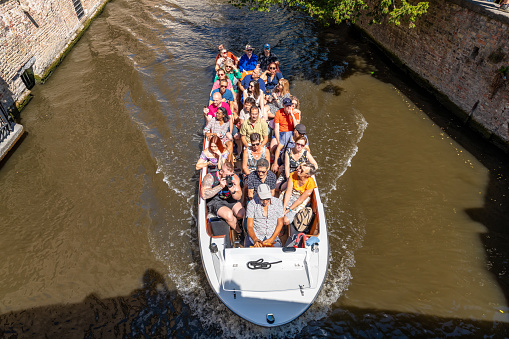 Bruges, Belgium. 16 July 2022. Tourists go on a popular boat tour of Bruges canals.