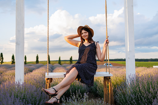 Pretty woman posing on a swing in a field