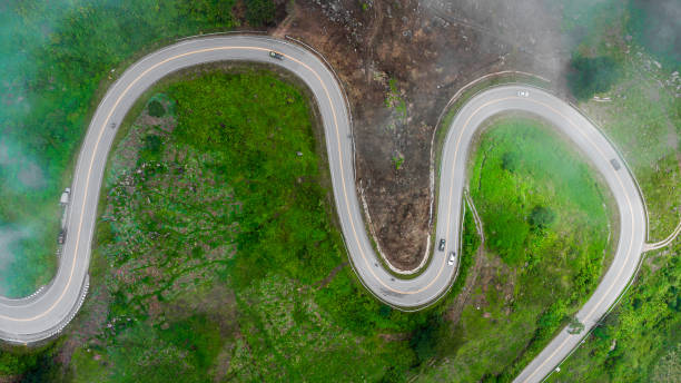 vista aérea de una curva de carretera que serpentea a través de las montañas. - thailand forest outdoors winding road fotografías e imágenes de stock