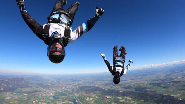 Skydivers fall upside down, in aerial flight They fly through the sky, over agricultural land by the Swiss Alps airborne sport stock pictures, royalty-free photos & images